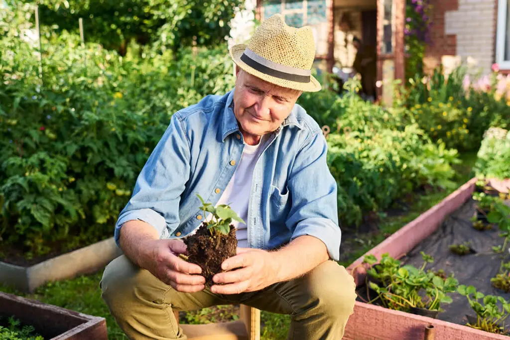 Elderly man sitting outside working in his garden