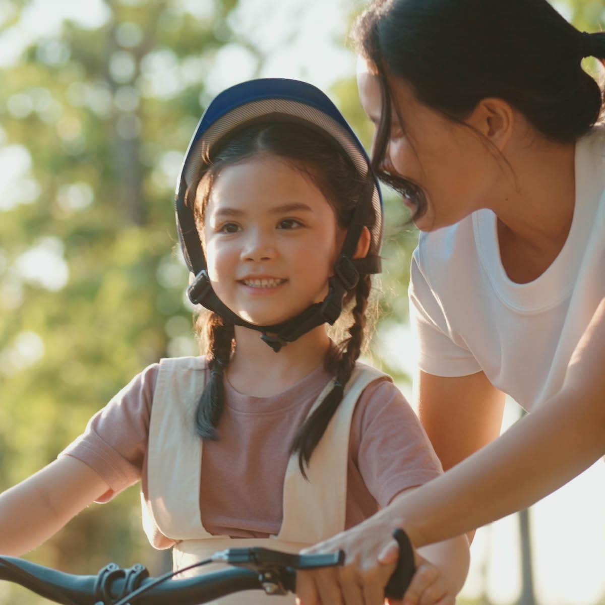 Mother teaching her young daughter how to ride a bike